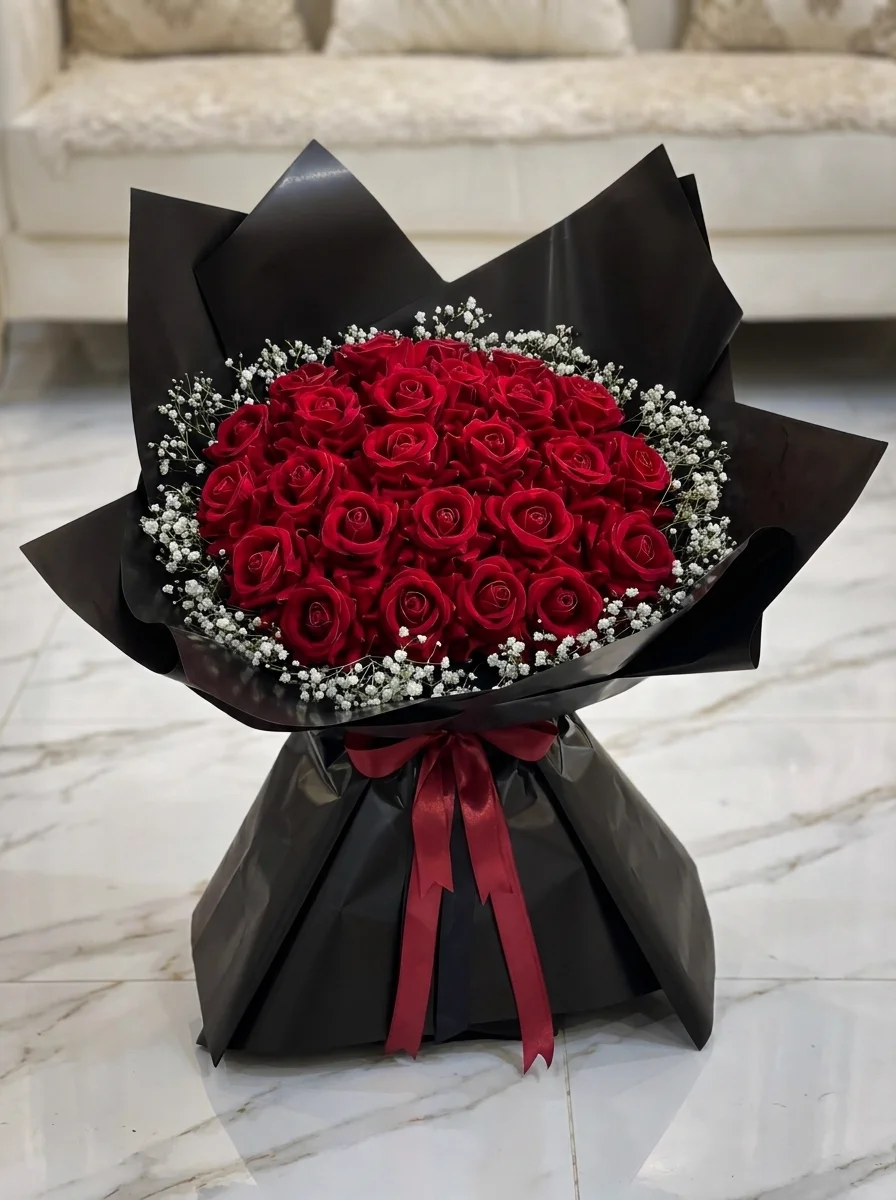 Elegantly draped red rose bouquet lined with dark foliage in sleek black wrapping